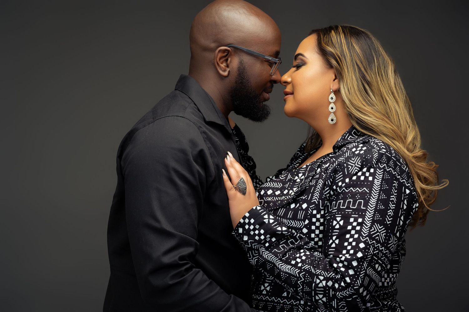 A romantic couple poses in black and white photos wearing matching black and white patterned outfits.