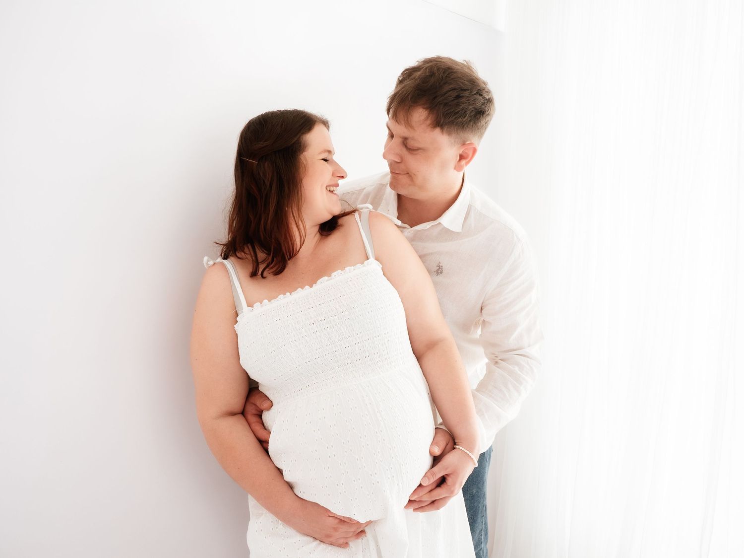 A pregnant couple laugh and smile during a photo session with Verity Photography