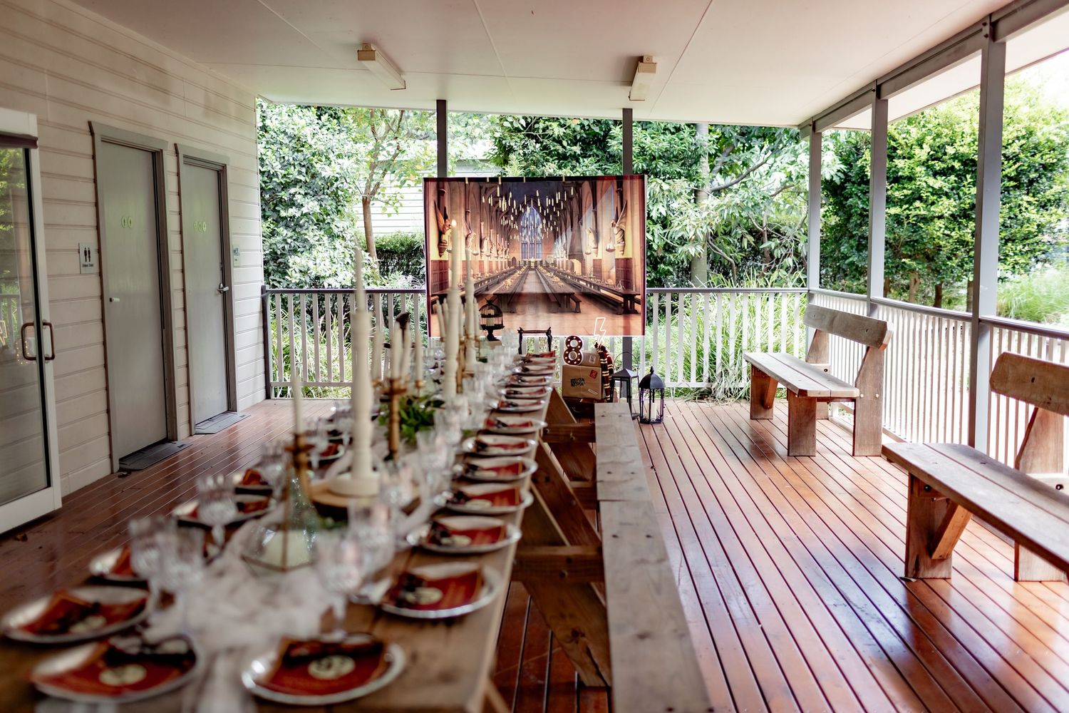 Elegant long dining table setup on a covered outdoor deck with rustic decor and natural lighting.