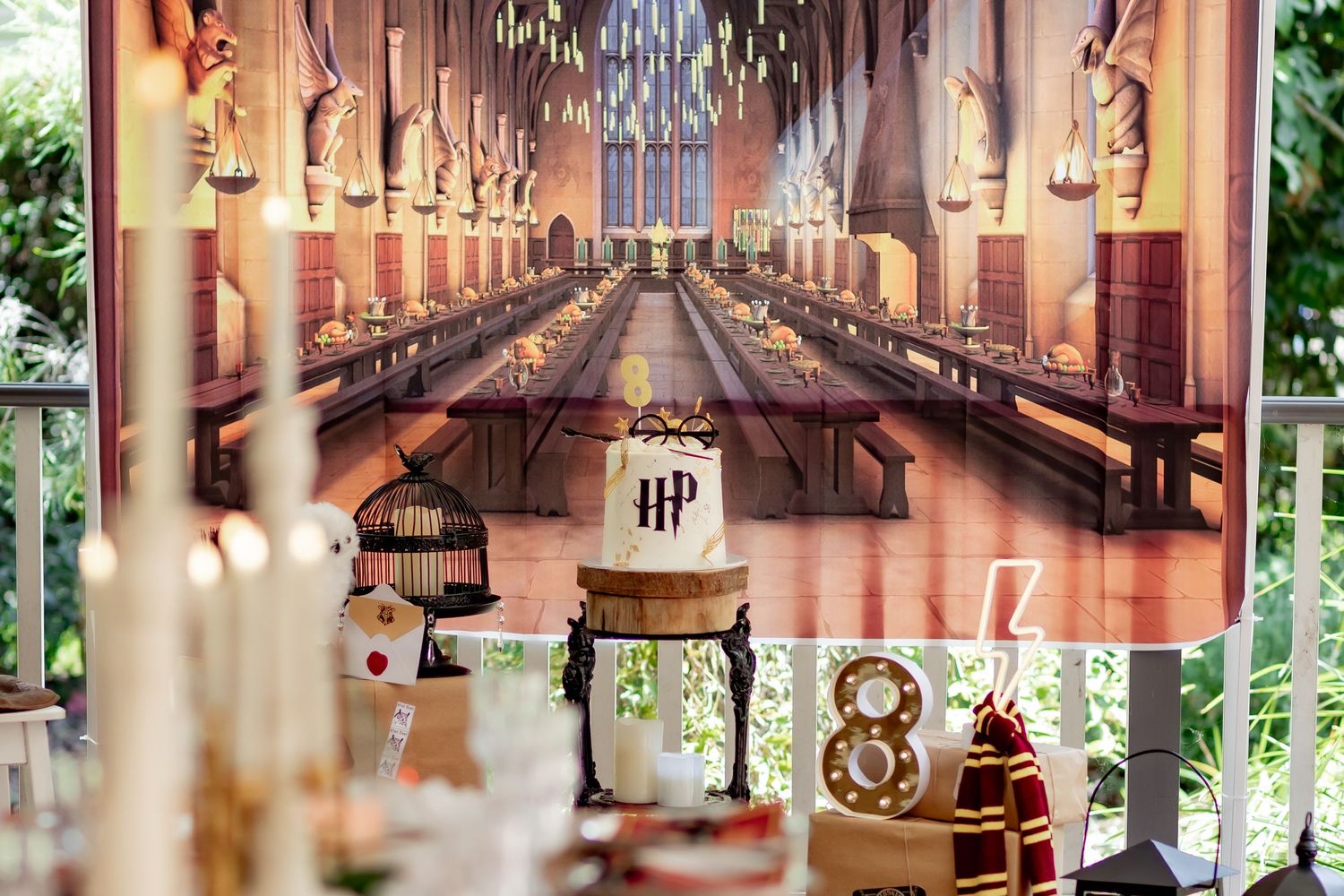 A detailed view of a Harry Potter themed party table with floating candles and castle backdrop.