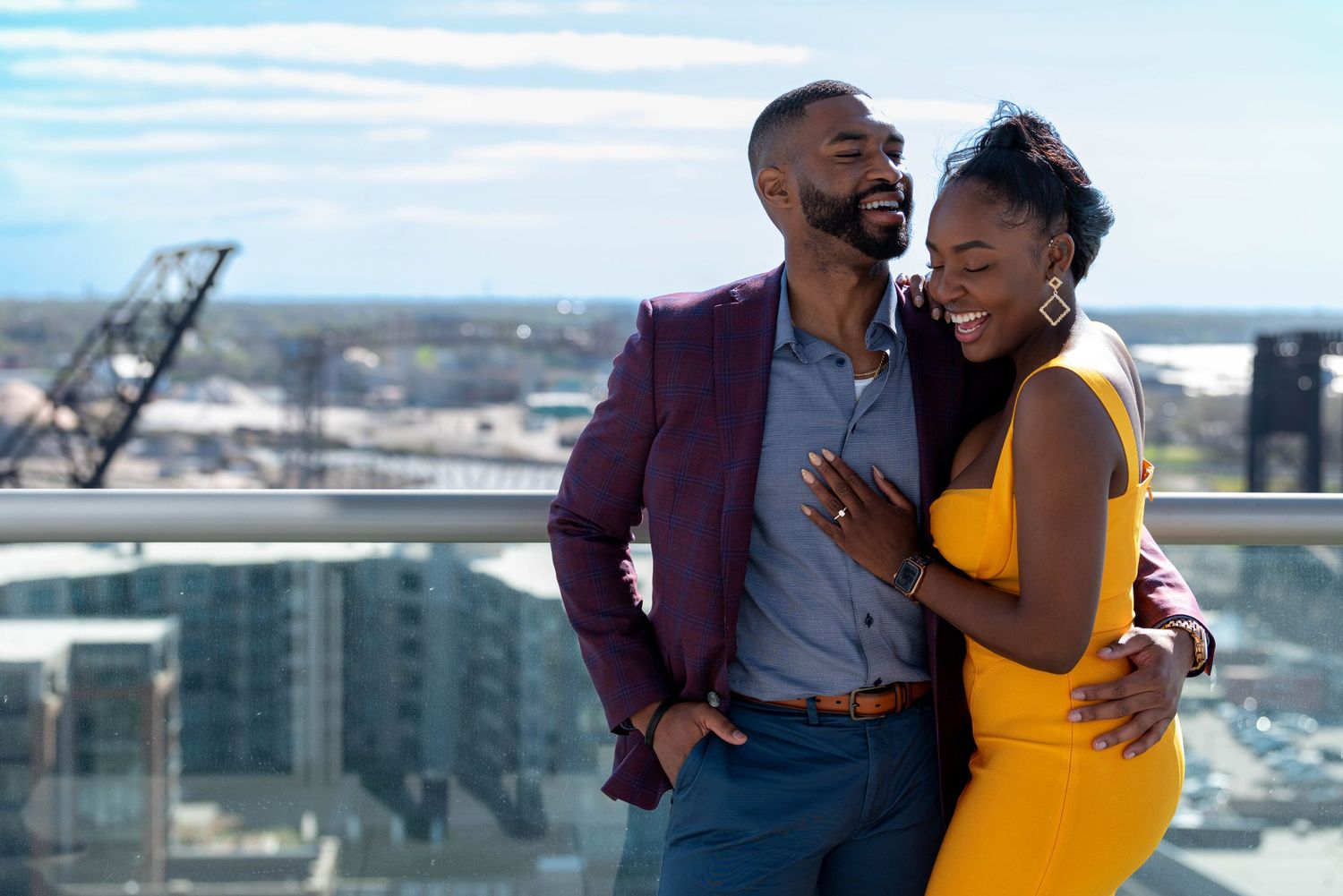 A couple shares romantic moments on a rooftop terrace with city views in the background.