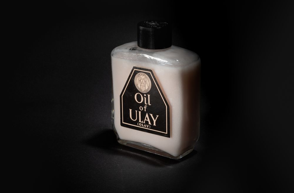 A vintage Oil of Olay beauty product bottle photographed against dark background.