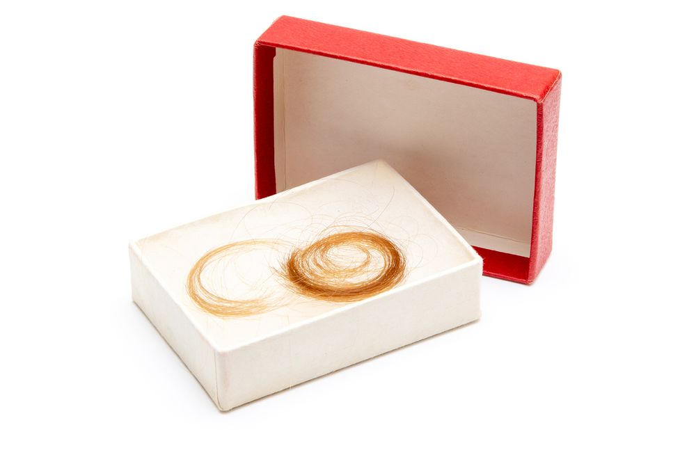 A jewelry box with rings displayed on cream colored padding inside a red container.