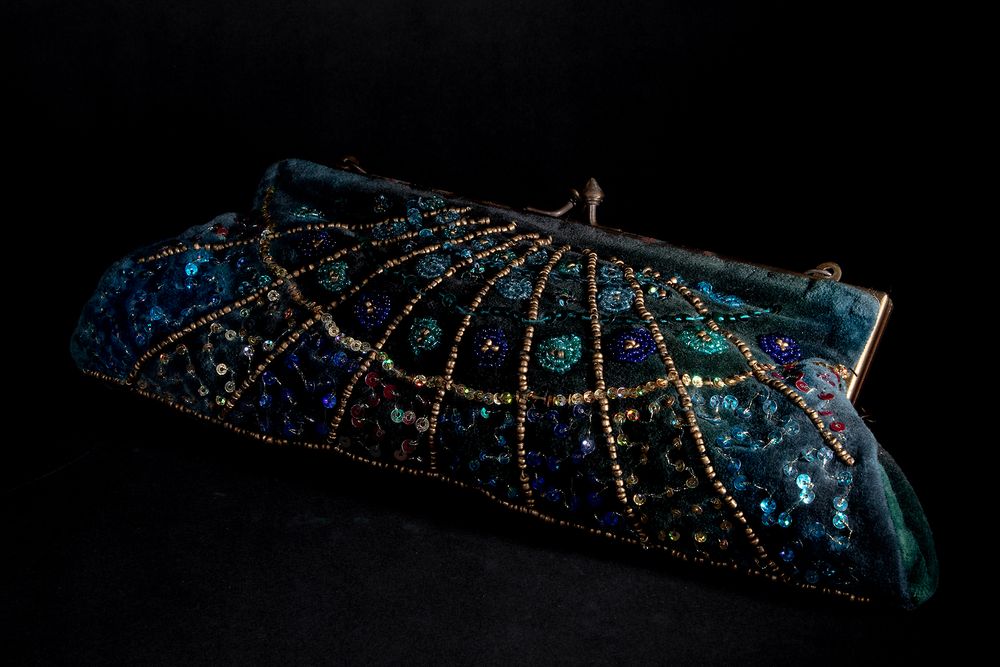 A sparkly blue beaded evening clutch purse photographed against black background.