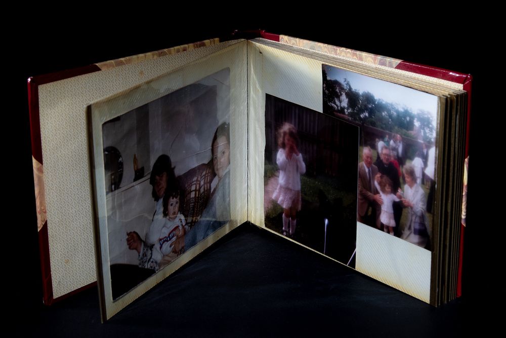 An open photo album displaying family photographs with dramatic lighting.