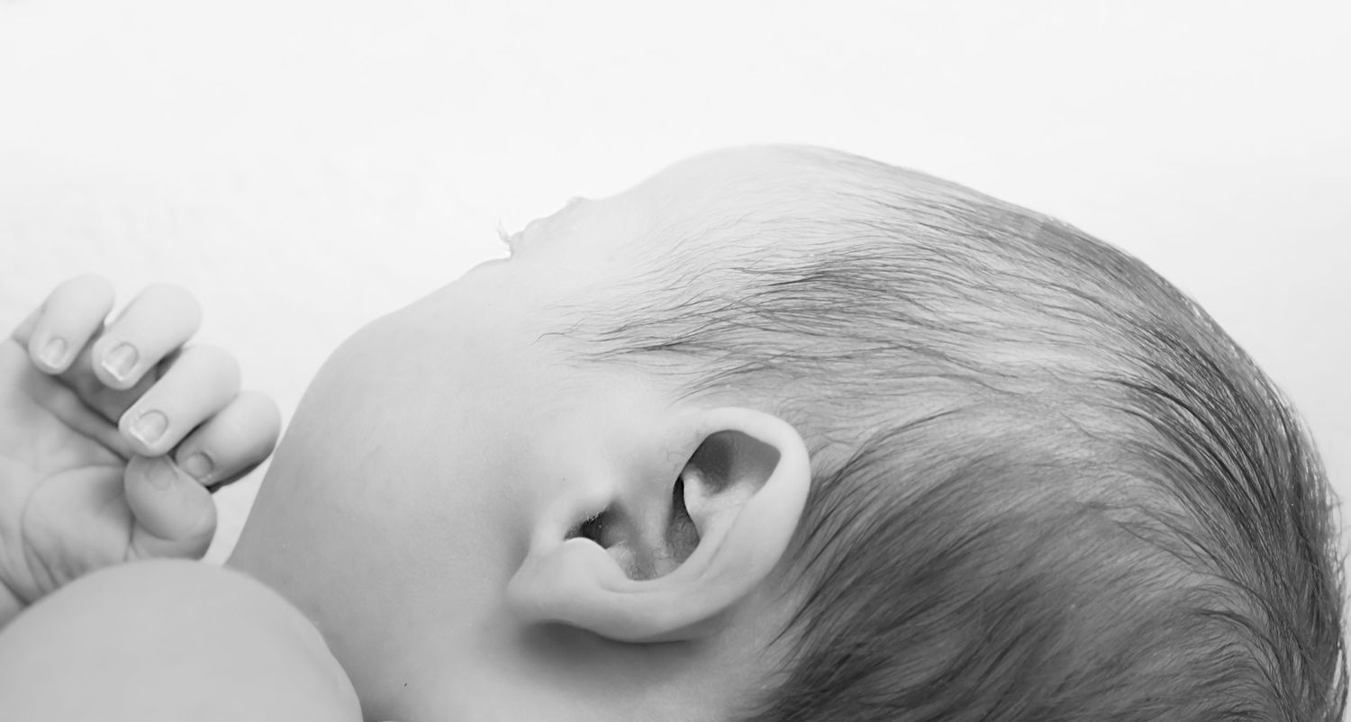 High-key black and white portrait of a sleeping newborn baby's profile.