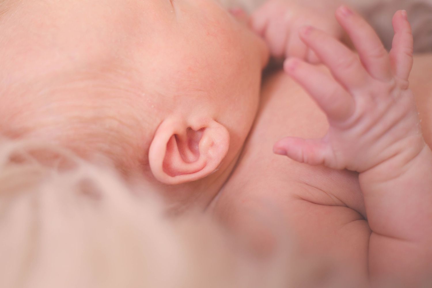 Delicate close-up of newborn features with soft pink tones.