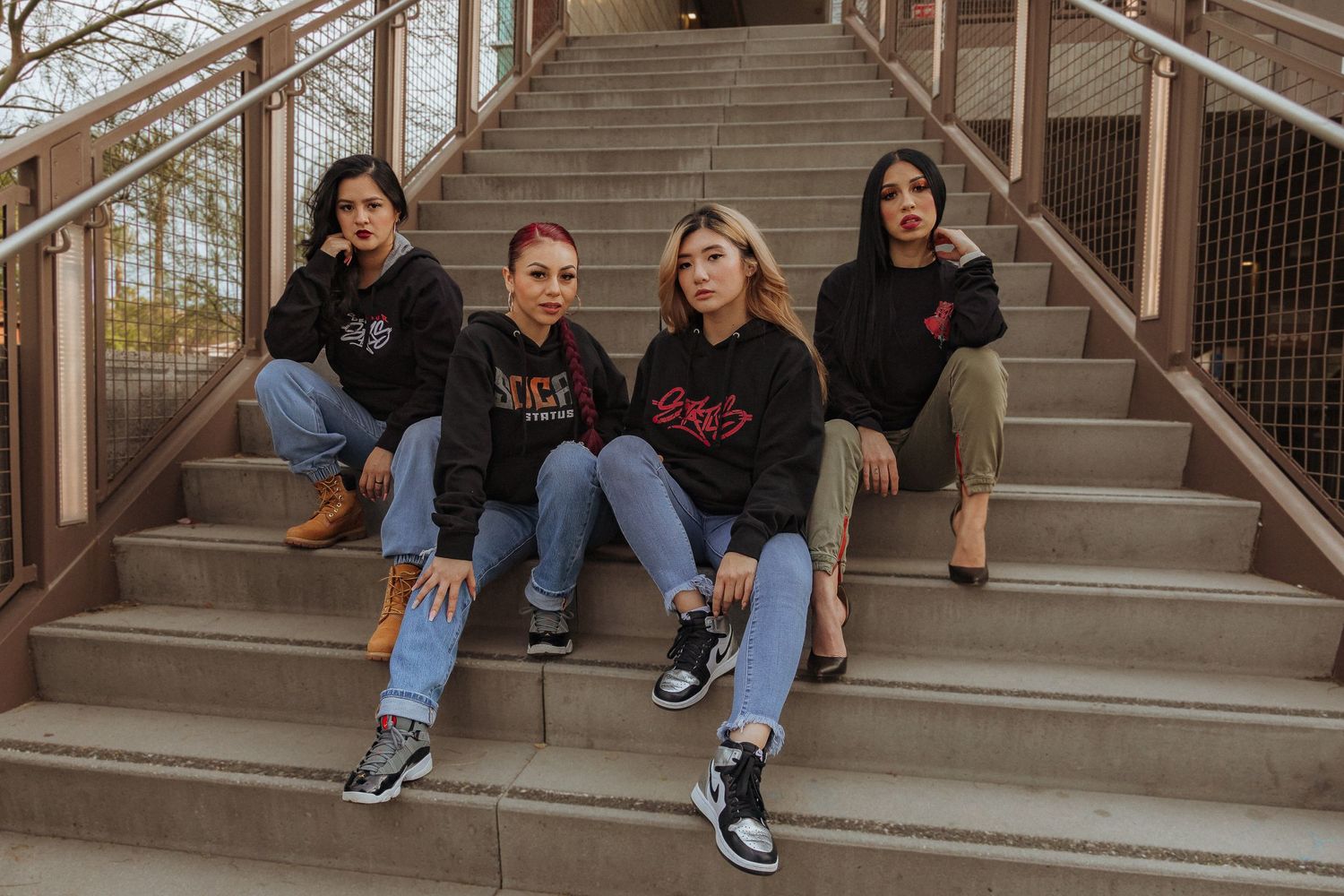 Group of friends in casual wear sitting together on concrete steps outdoors.