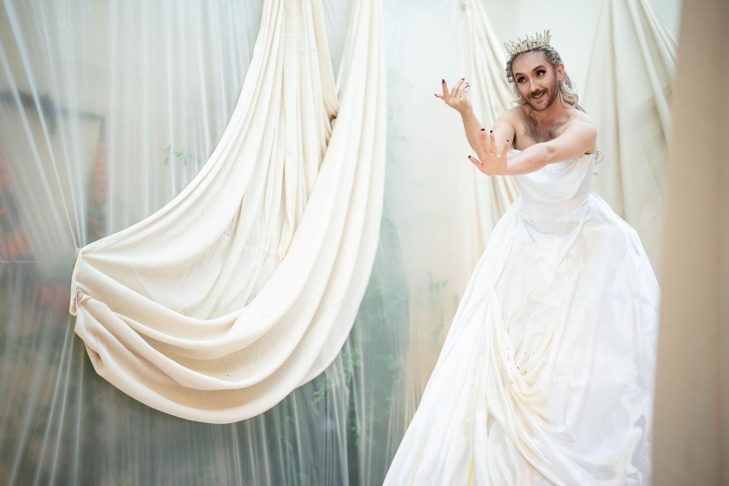 Bearded actor in a wedding dress beckons guests to play a game at an event near London