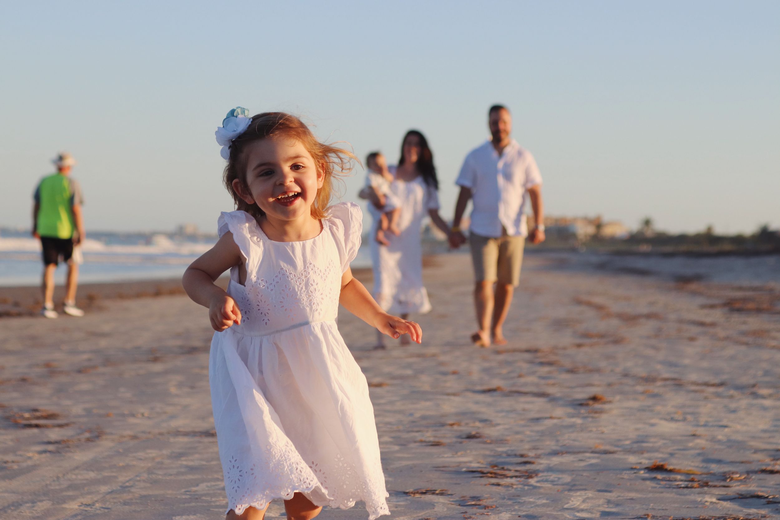 Little girl running with joy & family on Floridas East Coast Beaches