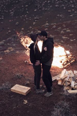 Couple on an adventure in the desert kissing in front of fire