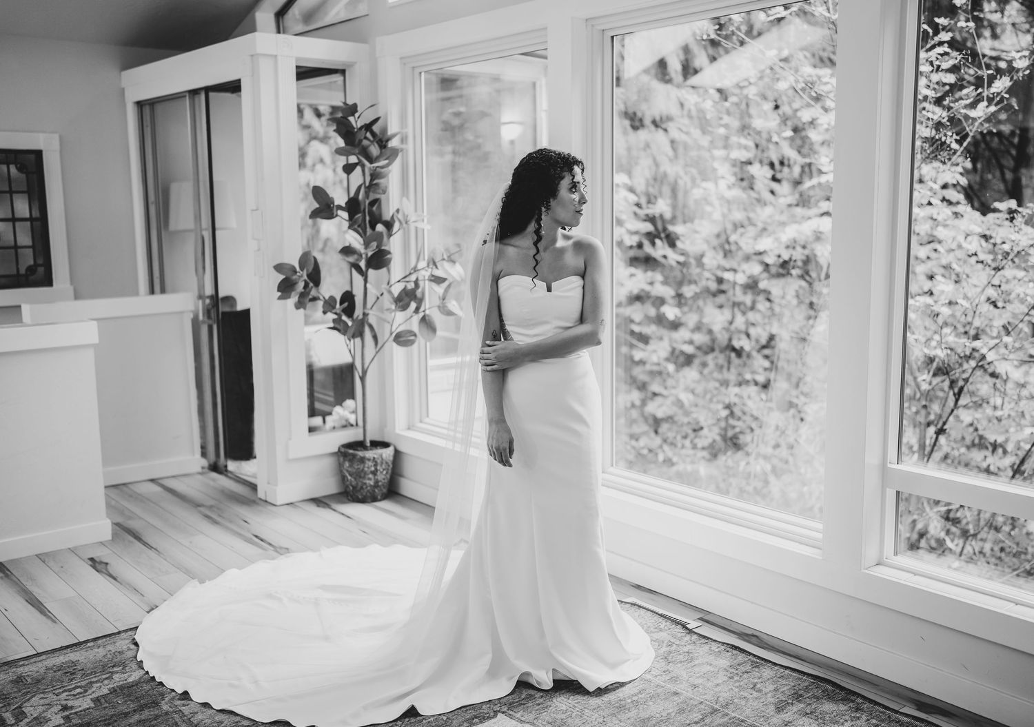 A wedding dress elegantly displayed in a bright sunlit room with floor-length windows.
