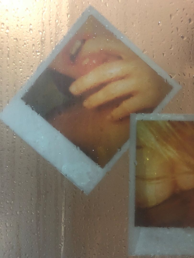Polaroid photographs behind rain-covered glass creating a dreamy effect.