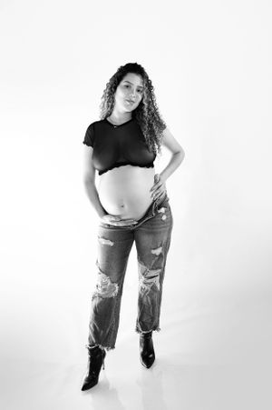 Black and white maternity photo with ripped jeans and crop top.