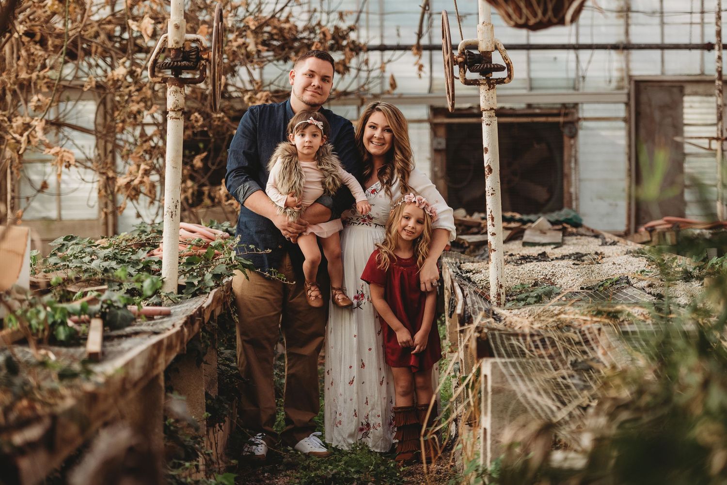 A rustic outdoor family portrait in front of a garden and weathered building.