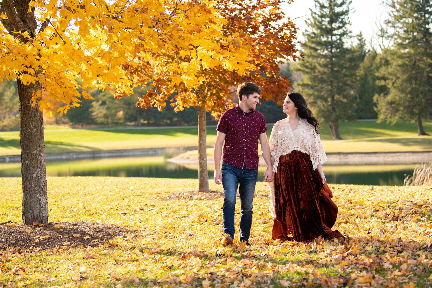 A couple walking beneath golden autumn trees during a fall photo session.