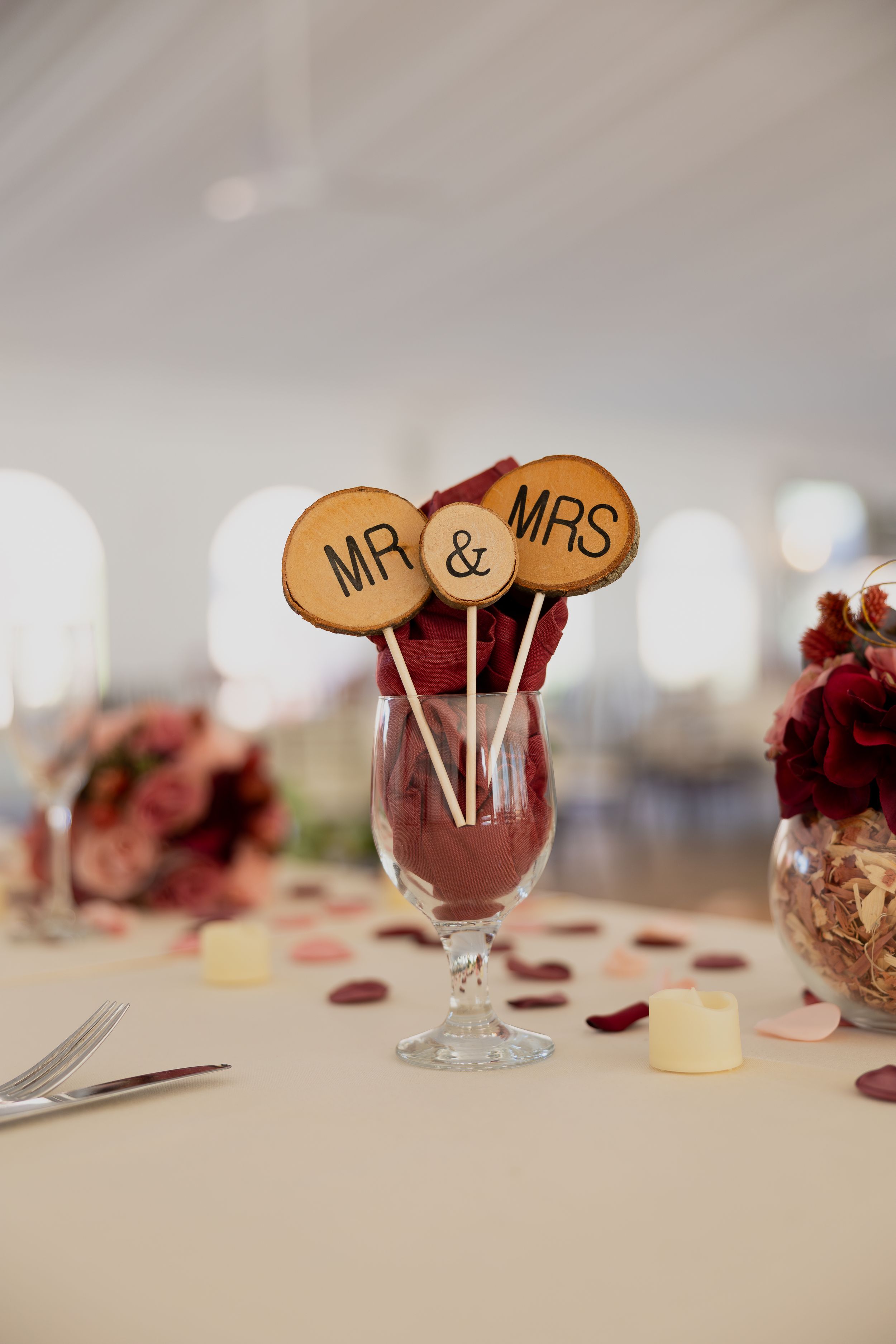 Wedding reception table setting with 'Mr & Mrs' wooden drink markers in wine glasses.