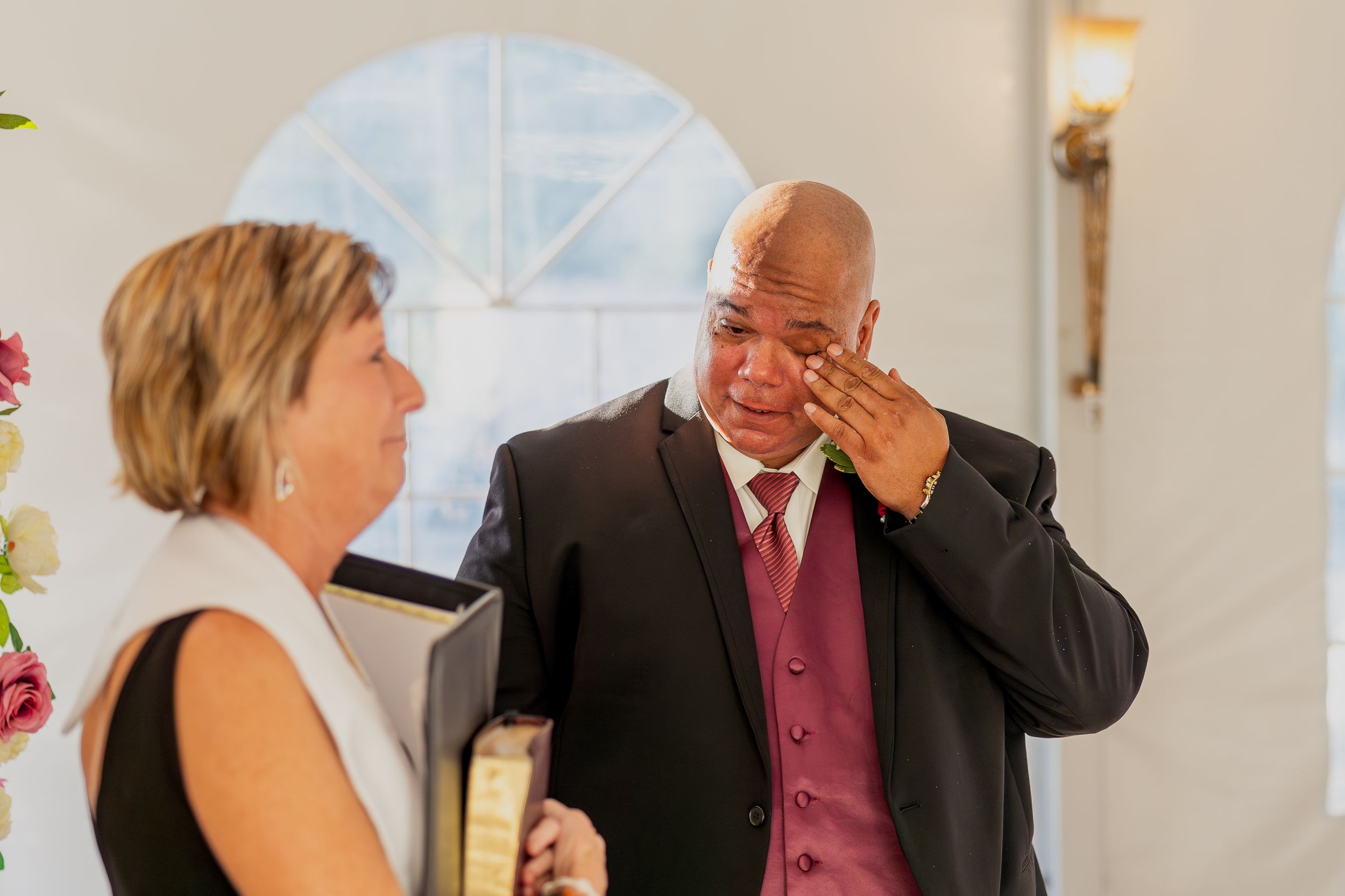 Wedding ceremony guests share joyful interactions in a light-filled reception space.