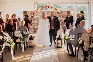 Wedding guests celebrate in decorated white tent venue with chandelier and lantern details.