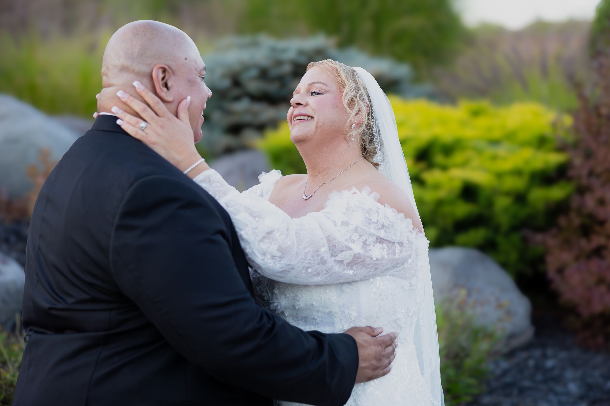 Wedding couple shares an intimate moment on beautifully landscaped garden patio.
