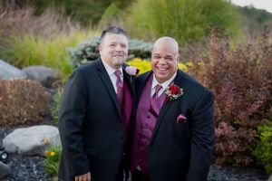 Loving couple shares a romantic moment in front of landscaped garden with colorful fall foliage.