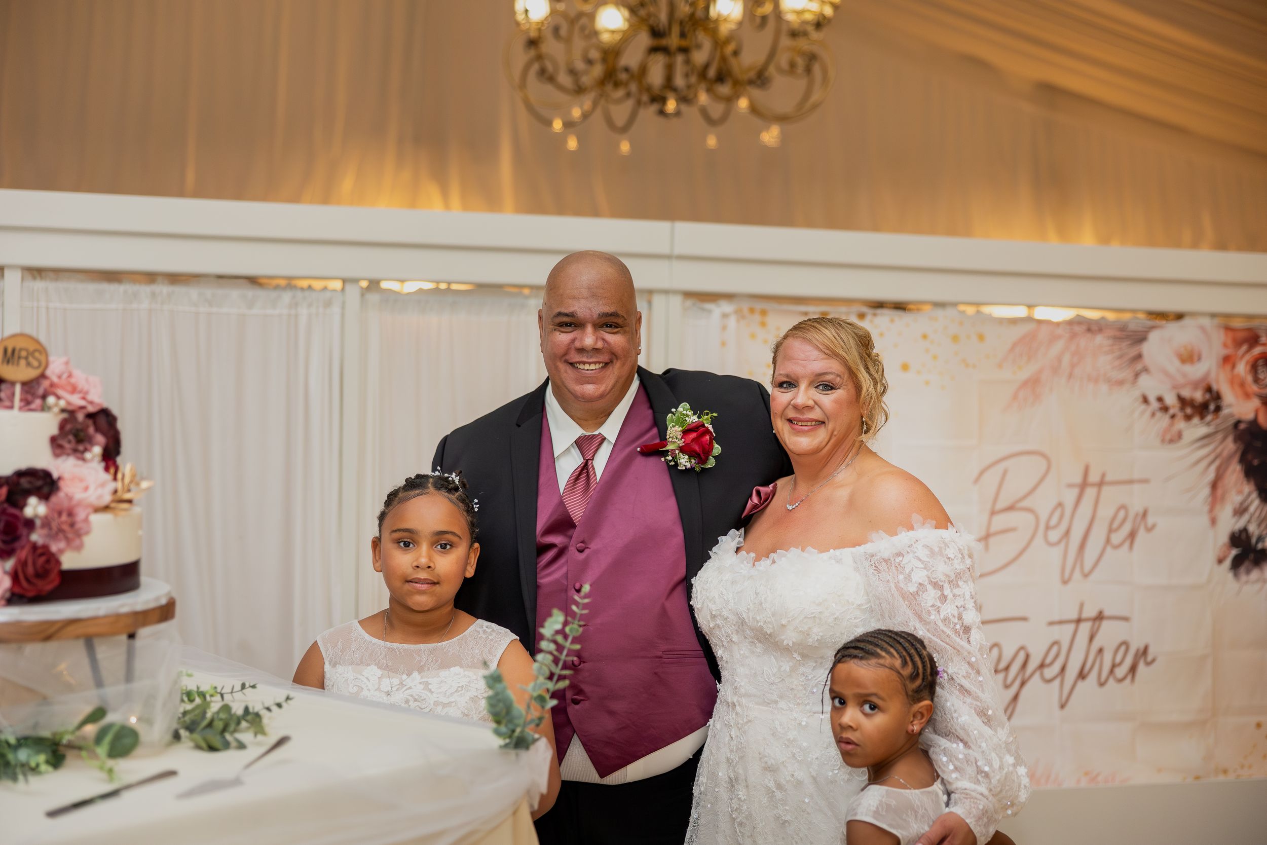 Wedding guests dancing and celebrating in an elegantly decorated reception hall with chandeliers.