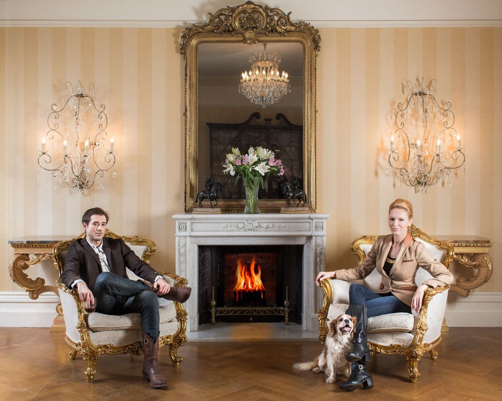 High-end environmental portrait of a couple in a grand drawing room for luxury branding.