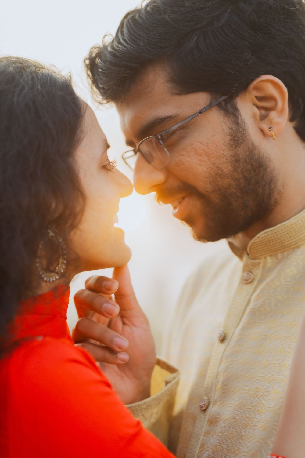 Romantic golden hour portrait of couple in traditional Indian attire sharing an intimate moment at sunset.
