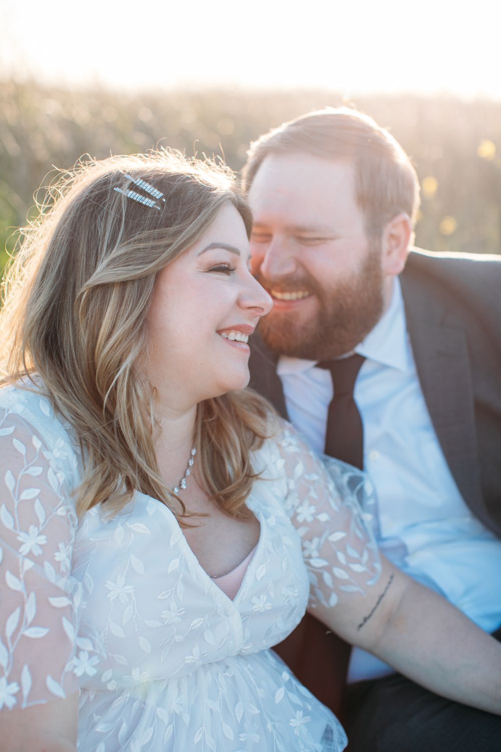 Joyful wedding couple laughing together in golden sunset light.