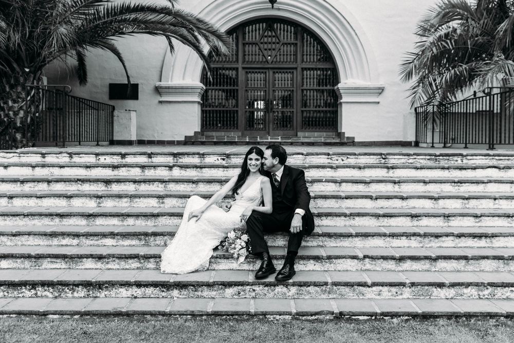 Black and white wedding photo of couple sitting on grand white stone steps.