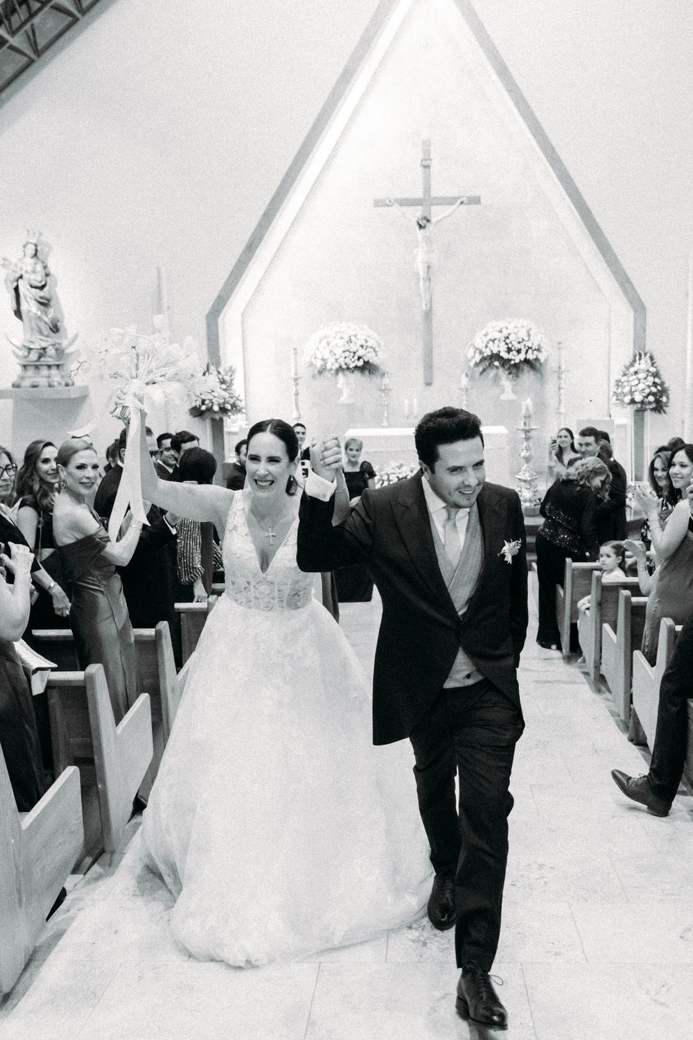 A joyful newlywed couple celebrates while walking down the church aisle after their wedding ceremony.