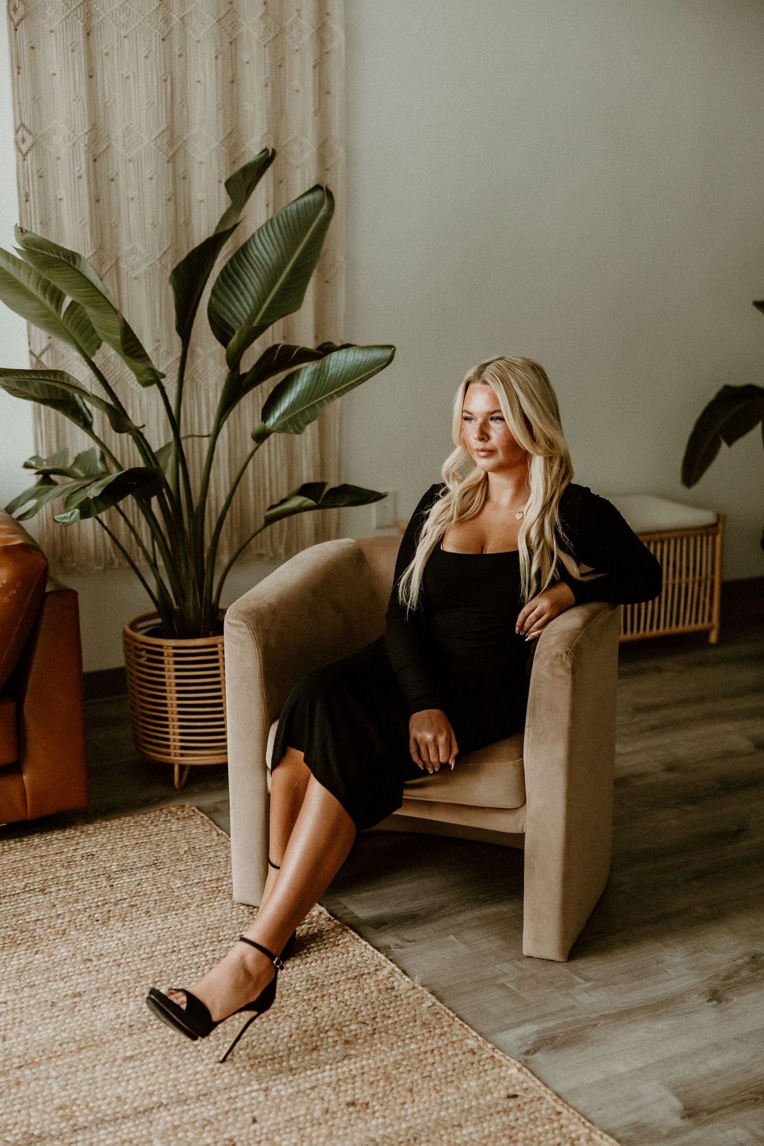 Lifestyle photo with black dress in modern room with large indoor plants.