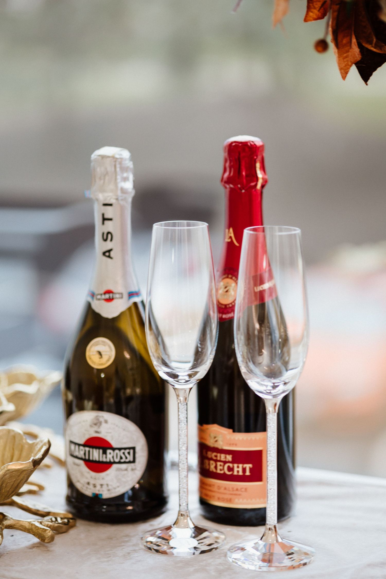 Two champagne bottles with empty flutes arranged on table with festive golden decorations.