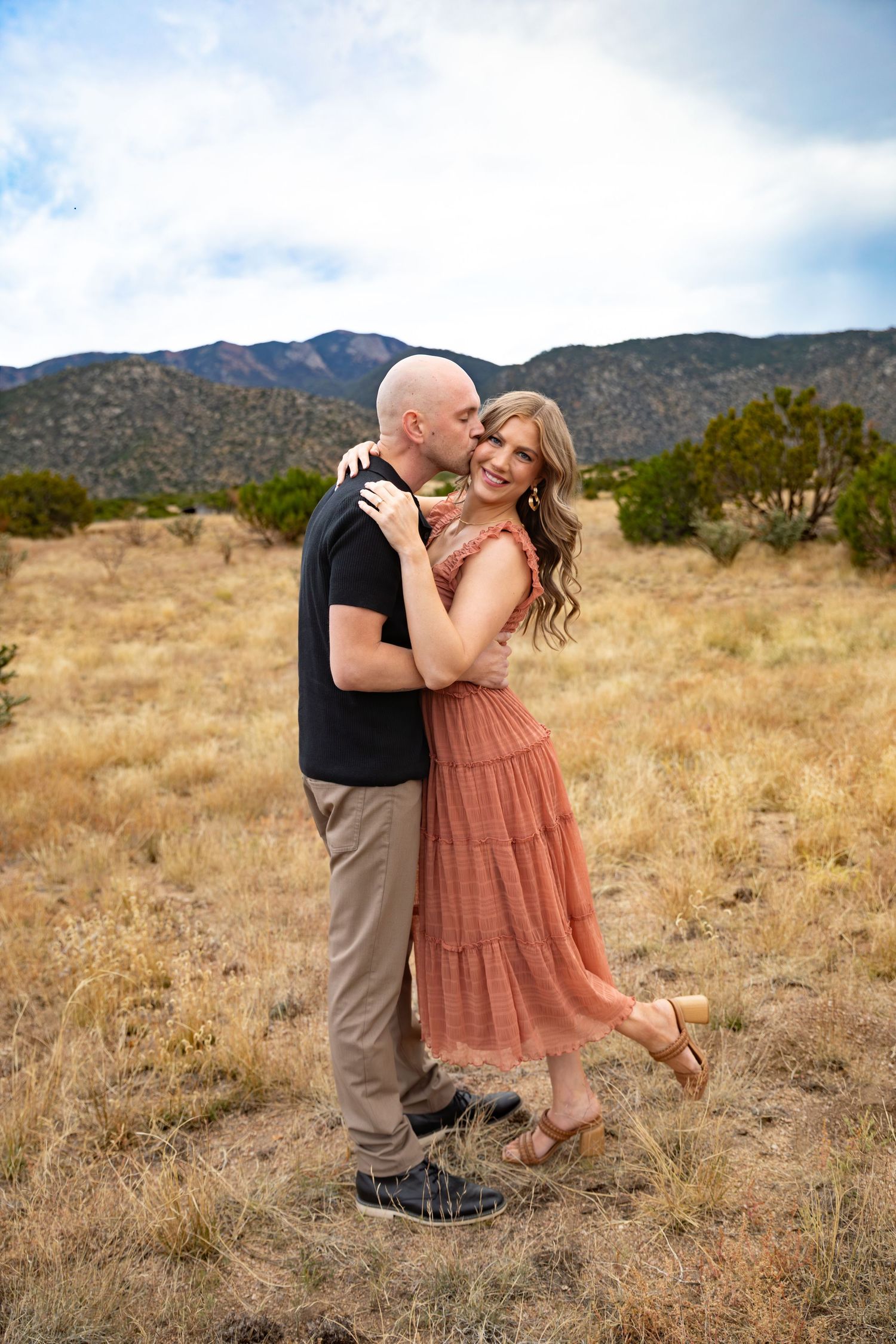 Loving couple shares an intimate moment in a field of sunflowers at sunset.