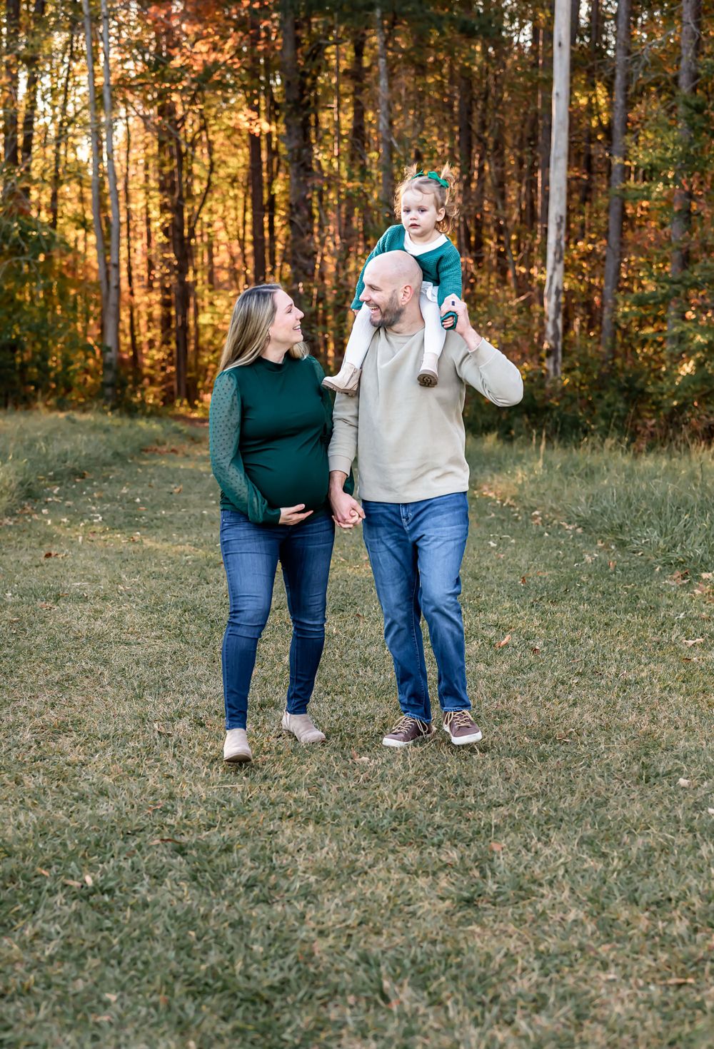 Family walking together in autumn forest during sunset.