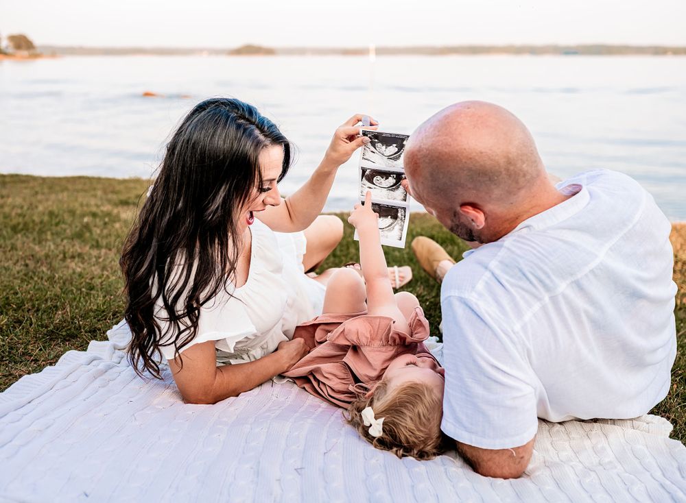 Happy family enjoying a playful moment together on a blanket by the water.