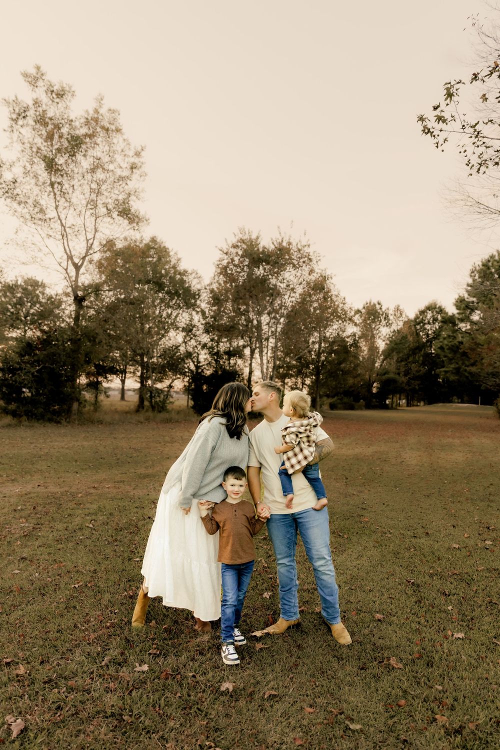 Candid family moment captured in a sepia-toned field during golden hour.