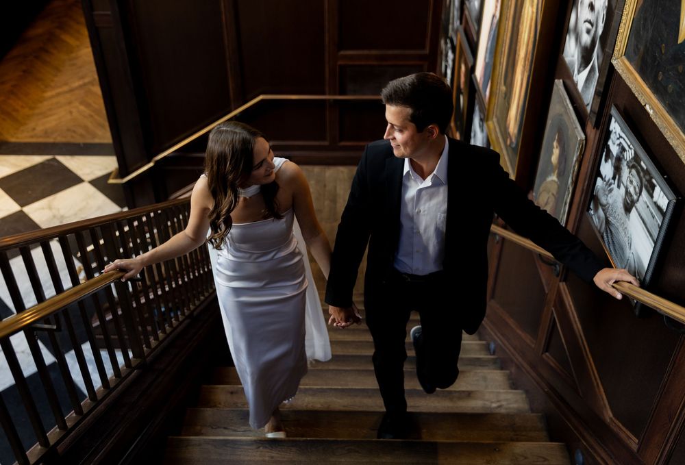 Orlando luxury wedding photographer a couple walking down elegant wooden stairs in formal attire.