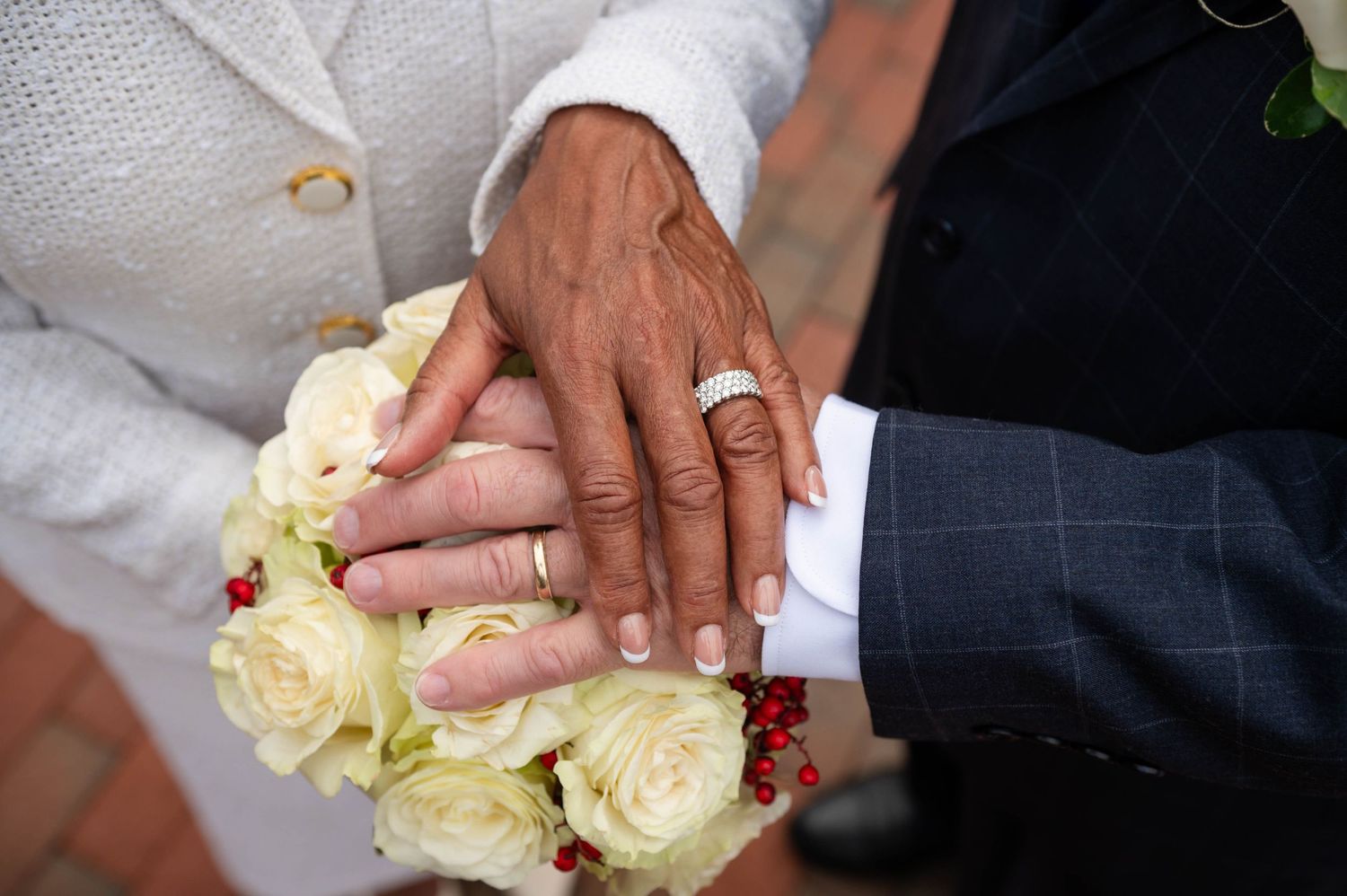 Close up of hands holding white roses during a wedding ceremony.