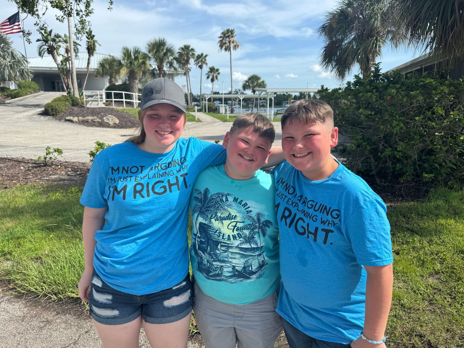 Group wearing matching blue t-shirts posing together at a tropical location.