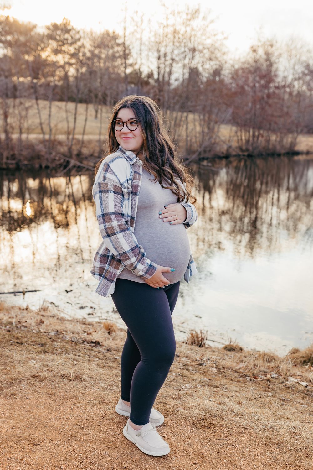 expectant mother happily holding baby belly during outdoor maternity session