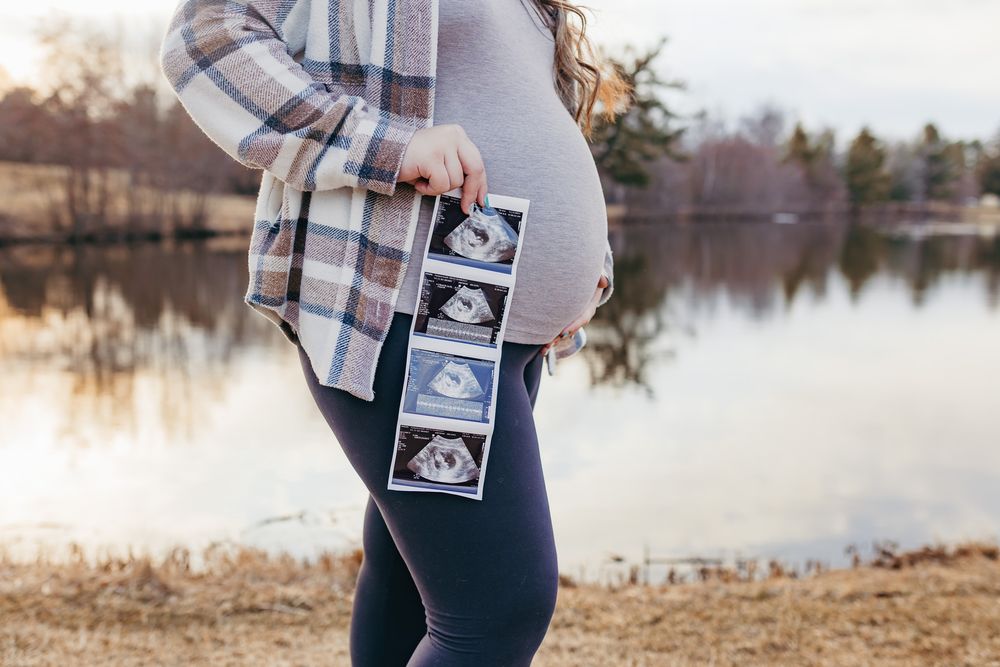 Detail photo of baby bump and ultrasound photos at sunset