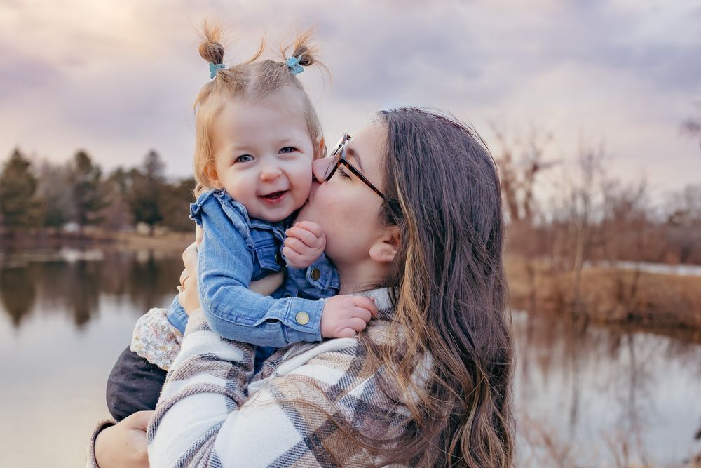 Mo giving toddler a big kiss during their outdoor maternity session in Wausau, Wisconsin