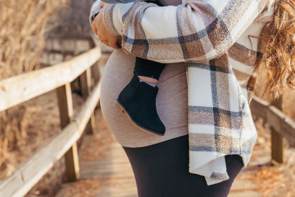 Detail photo of moms belly while holding big sister during their maternity session
