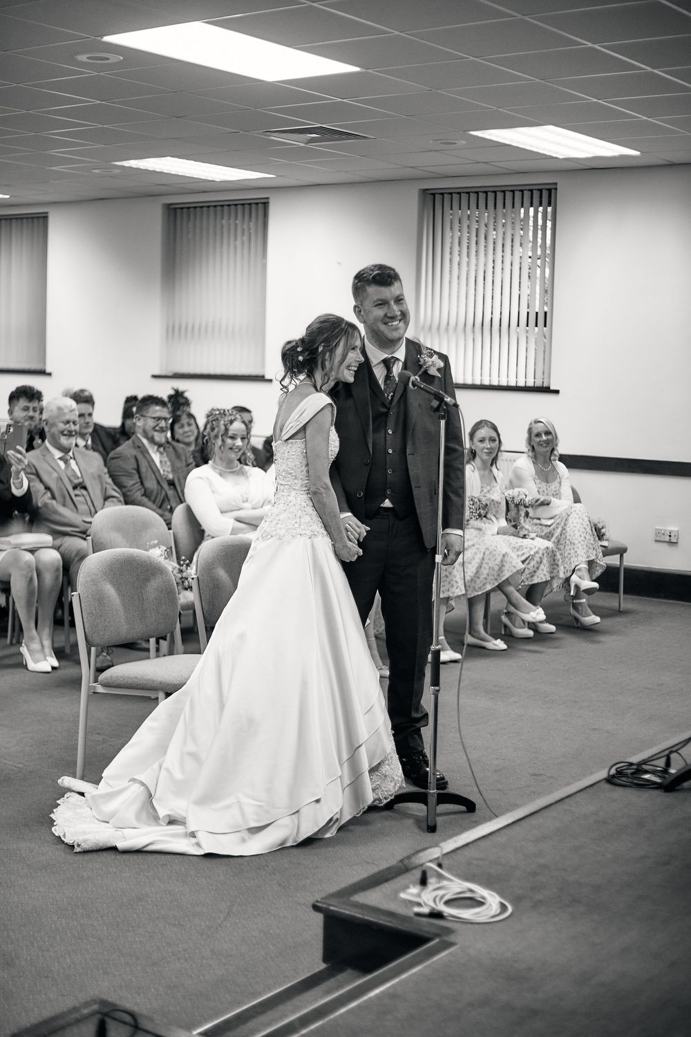 A sequence showing attendees at a wedding ceremony seated in chairs as a bride kneels down in her white gown.