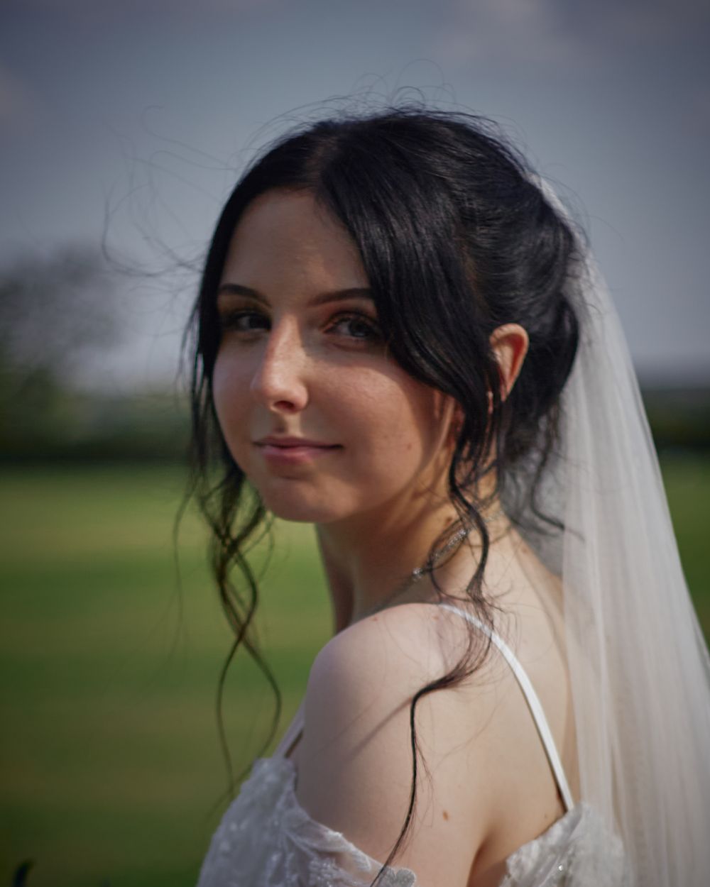 Romantic bridal portraits showing delicate lace details and flowing veil against outdoor backdrop.