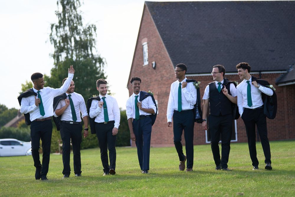 Wedding party walking in casual formation along path wearing blue and white formal attire.