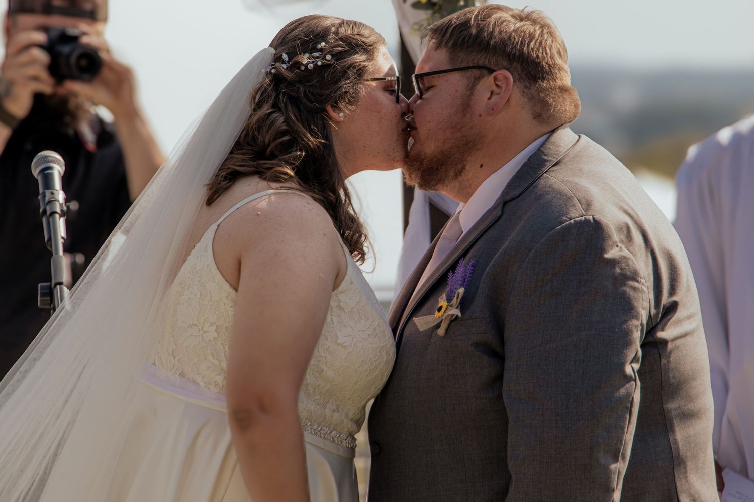 Bride and groom sharing first kiss at outdoor wedding ceremony.