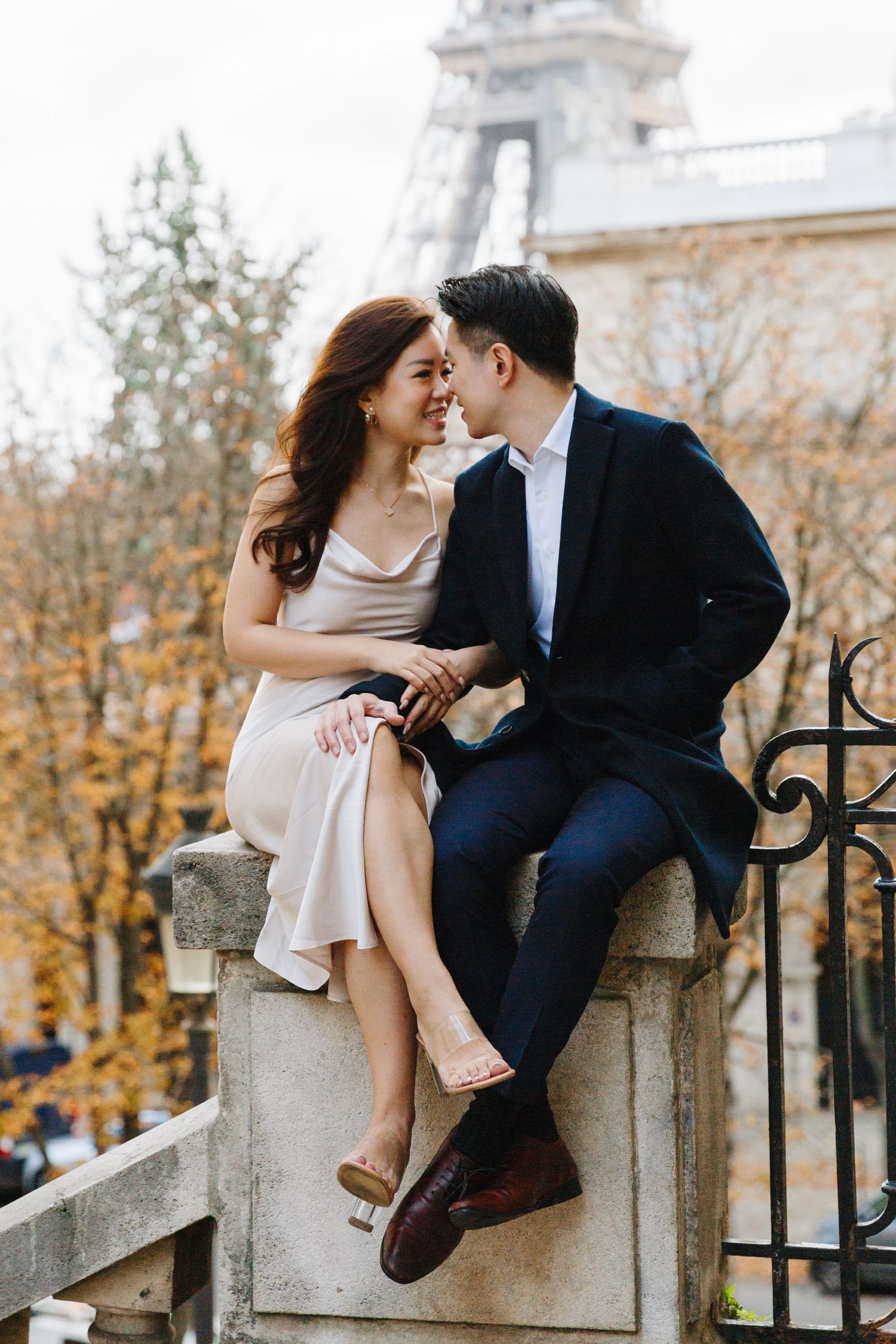 Elegant couple sitting together and laughing during a romantic outdoor session in Paris.
