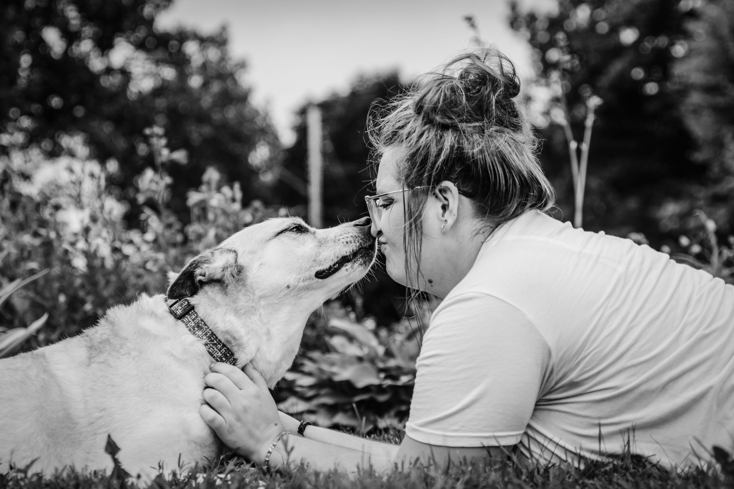 Black and white photo of playful moment between person and white dog outdoors.